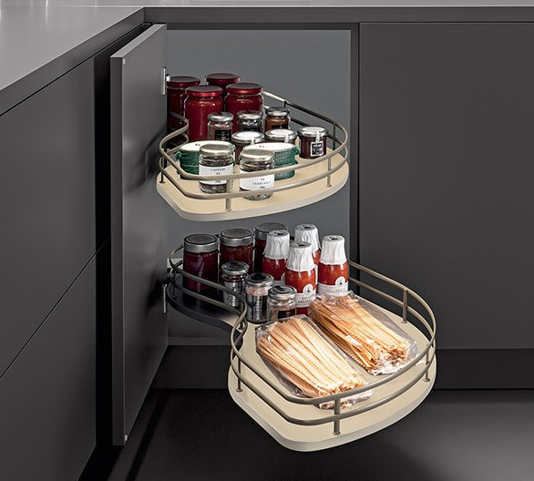 Corner kitchen cabinet with rotating trays filled with jars and bottles.